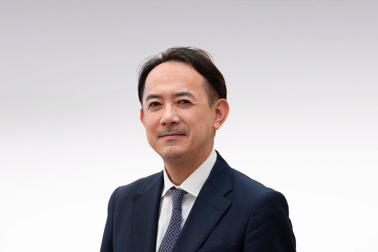 川邊健太郎 プロフィール写真（スーツ・白背景・笑顔）
